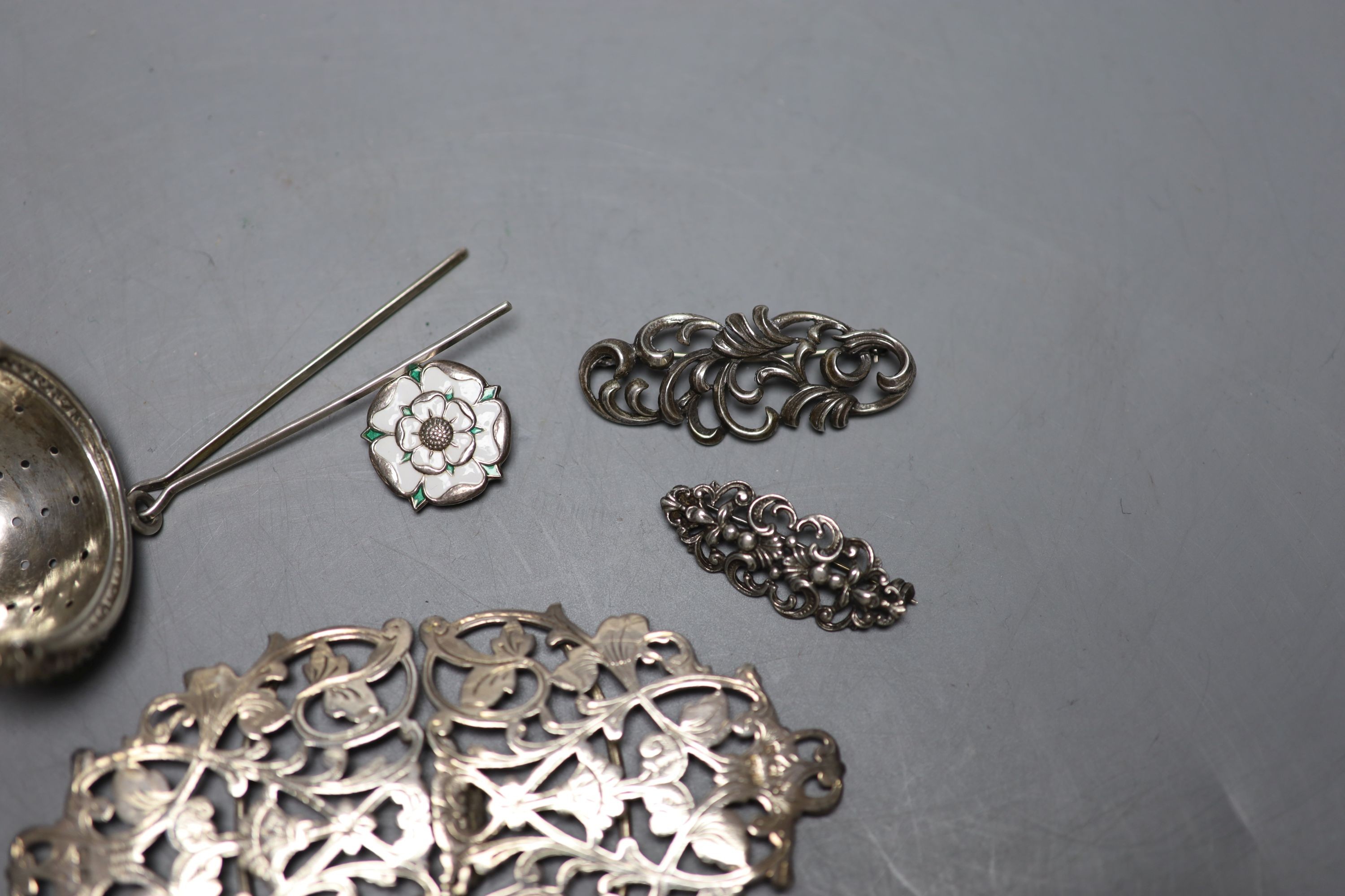 An Edwardian pierced silver belt buckle, Birmingham, 1901, 11.2cm, two brooches , rose brooch and a tea strainer.